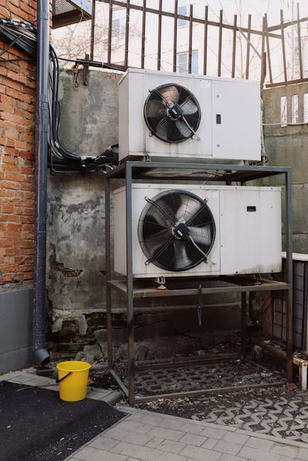 Two industrial air conditioning units mounted outdoors against a brick wall, emphasizing HVAC technology.
